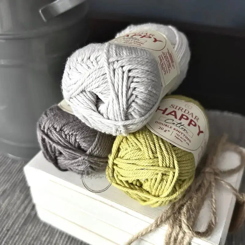 The balls of yarn, used in this crochet kit, are sitting on a white wooden board.