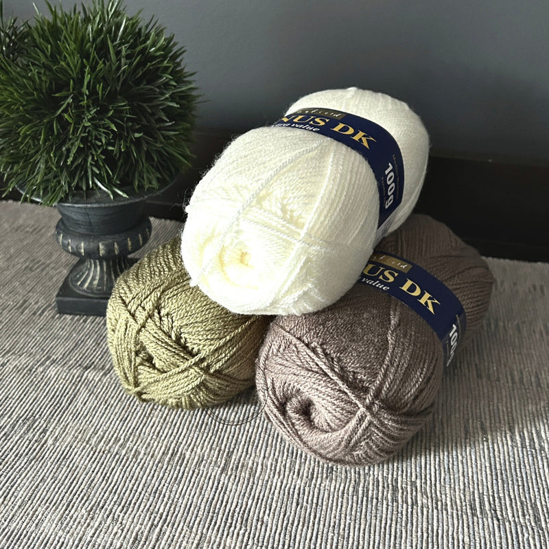 The 3 (out of 5) balls of yarn, that come in this crochet kit, are sitting on a table.