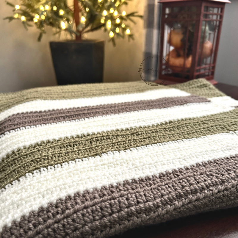 The finished baby blanket, made from this crochet kit, is draped over a table with Christmas lights.