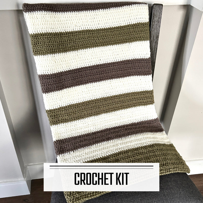 A crochet kit for a baby blanket. The finished blanket is lying over a chair.