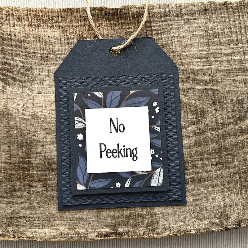 A finished tag, from this gift tag kit, sitting on a wooden board.