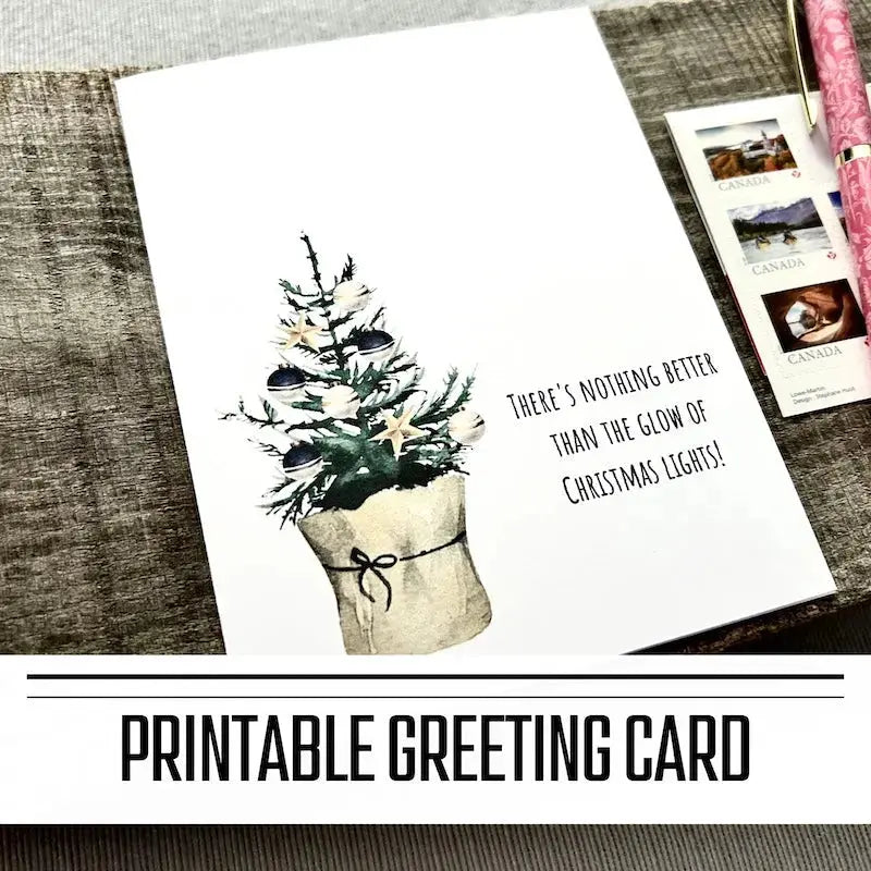A printable greeting card for Christmas. The finished card is sitting on a wooden board with a pen and stamps.