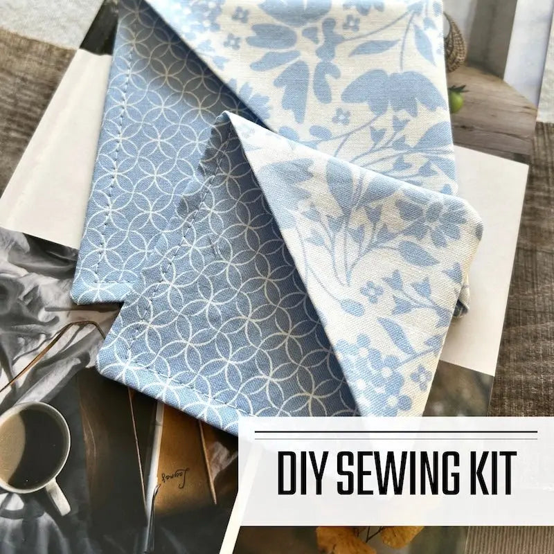 This is a DIY sewing kit for a corner bookmark. The finished corner bookmarks are lying on a book that is on a wooden board.