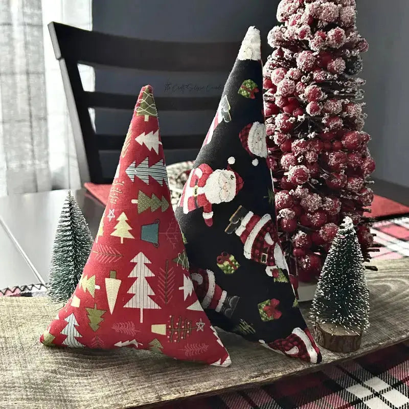 The 2 Christmas trees, made from this sewing kit, are sitting on a wooden board.