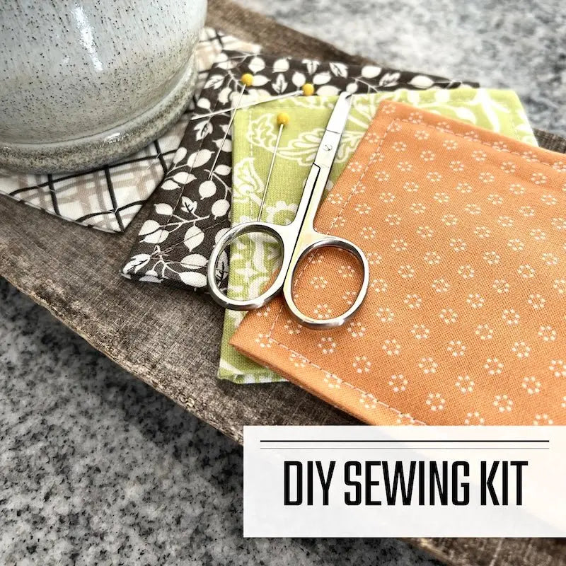 A DIY sewing kit for a quilted coaster set. The finished coaster set is lying on a wooden board.