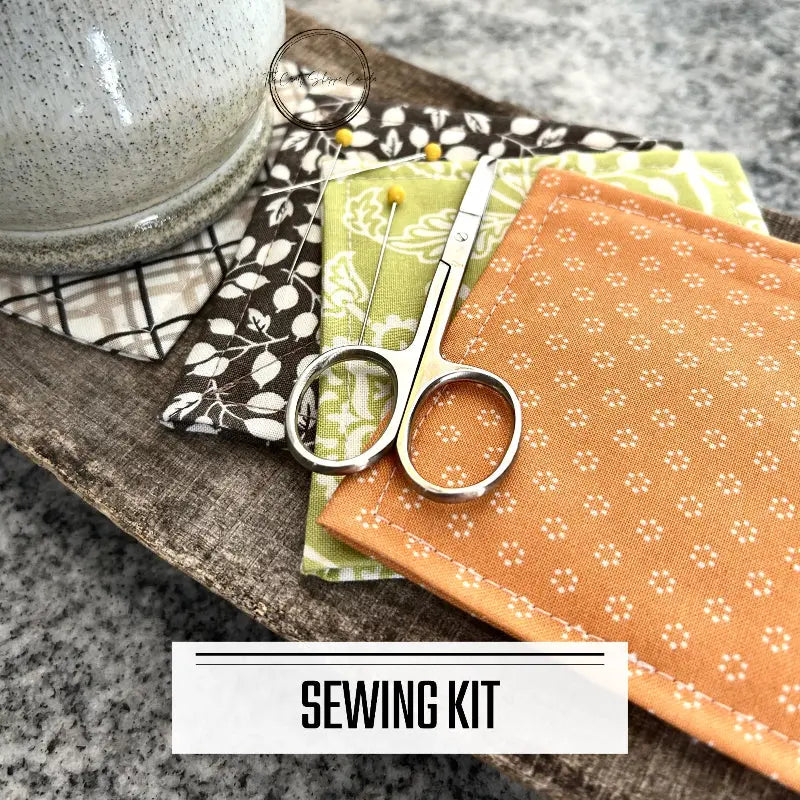 A DIY sewing kit for a quilted coaster set. The finished coaster set is lying on a wooden board.