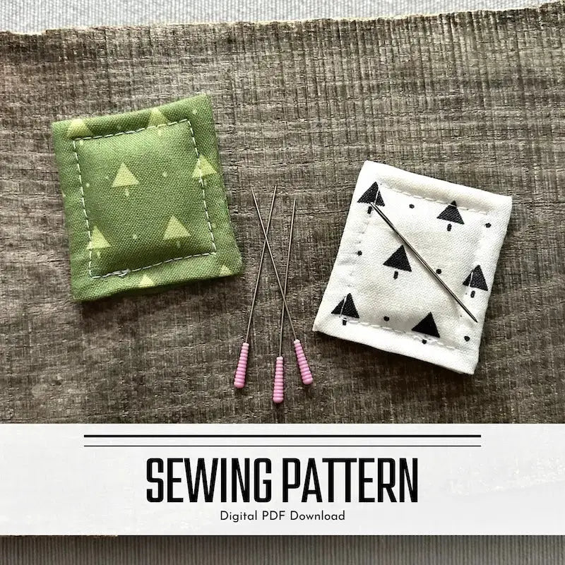 A DIY sewing pattern for a needle minder/fridge magnet. There are 2 needle minders lying on a wooden board sewing pins and a sewing needle.