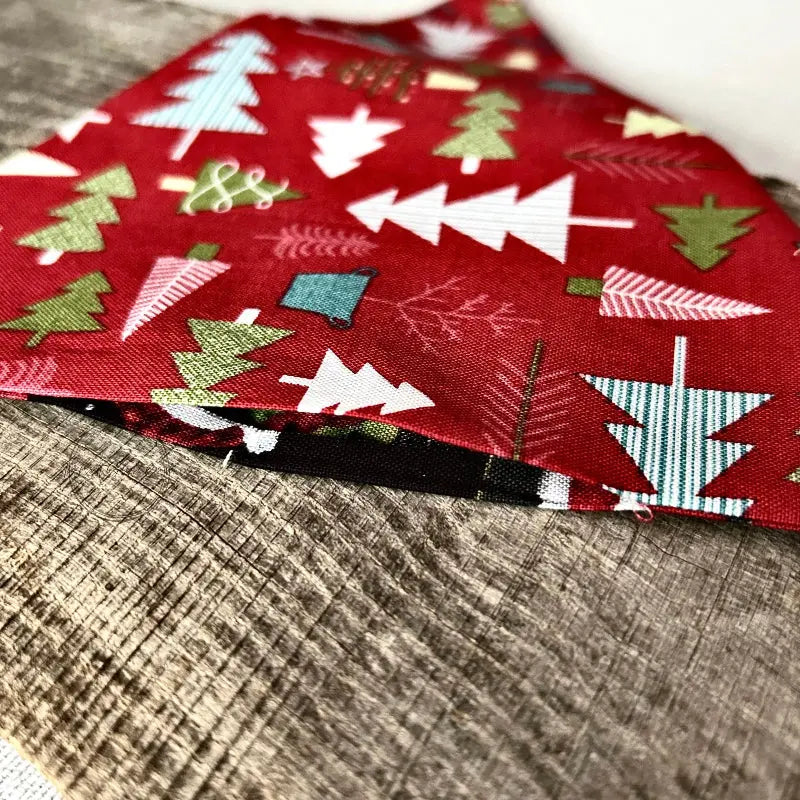 One of the Christmas trees, made from this sewing pattern, is in the process of being made and is lying on a wooden board.