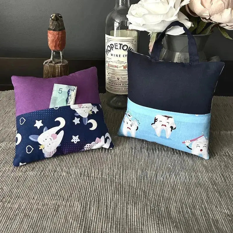 The tooth fairy pillows, from this sewing kit, are sitting on a buffet with money peeking out of the pocket.