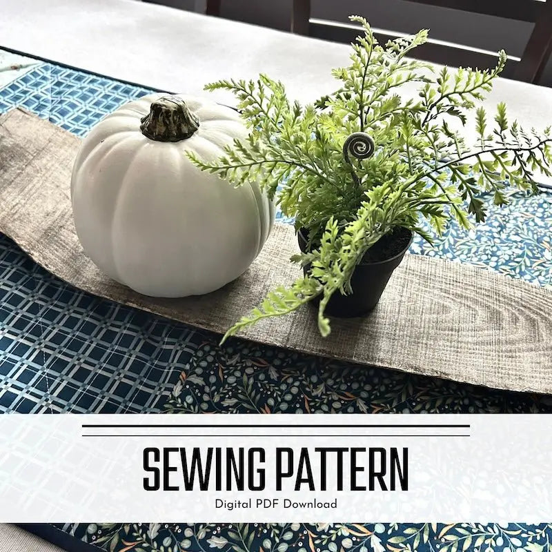 A digital PDF sewing pattern for a quilted table runner. The table runner is lying on a wooden board on a table.