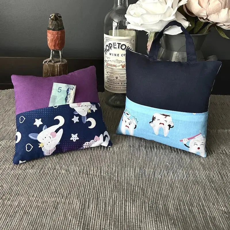 The tooth fairy pillows, from this sewing kit, are sitting on a buffet with money peeking out of the pocket.