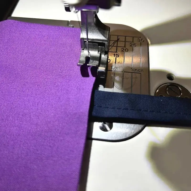 The purple pillow is under a sewing machine needle ready to be sewn.