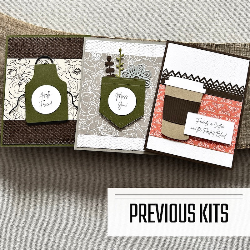 There are 3 finished cards, sitting on a wooden board, to show what cards have been sent in previous kits.