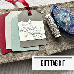 A DIY gift tag kit for Christmas. Finished tags are sitting on a wooden board with a roll of twine and a tape runner - The Craft Shoppe Canada 