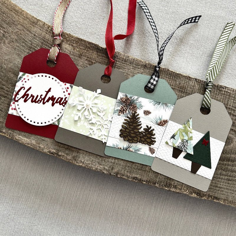 There are 4 finished tags, sitting on a wooden board, to show the finished gift tags that are included in this kit - The Craft Shoppe Canada