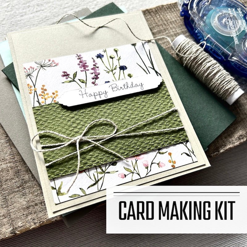 A DIY greeting card kit for Happy Birthday cards. A finished card is sitting on blank cards with a roll of twine and a tape runner - The Craft Shoppe Canada 