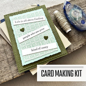 A DIY greeting card kit for cards with funny sentiments. A finished card is sitting on blank cards with a roll of twine and a tape runner - The Craft Shoppe Canada