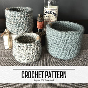 A digital crochet pattern for a set of 3 crocheted baskets. The baskets are sitting on top of a buffet - The Craft Shoppe Canada