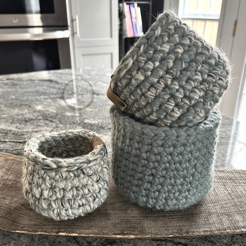 The crochet baskets are sitting on a wooden board on top of a counter - The Craft Shoppe Canada