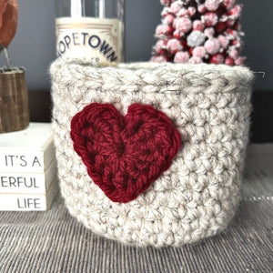 The heart basket is sitting on a buffet with a spring bird beside it - The Craft Shoppe Canada