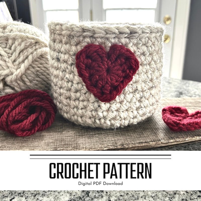 A crochet pattern for a Valentine heart basket. The basket is sitting on a wooden board with yarn and a red heart beside it - The Craft Shoppe Canada