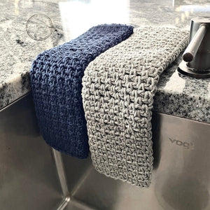 This is a photo of the finished washcloths. One is navy and one is grey and they both use the moss stitch - The Craft Shoppe Canada