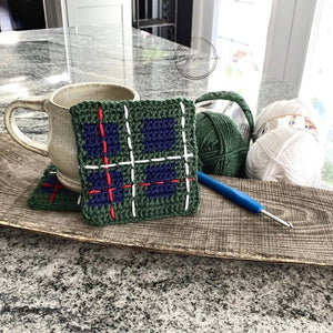 This photo features the finished set of coasters with the yarn that was used along with a crochet hook - The Craft Shoppe Canada