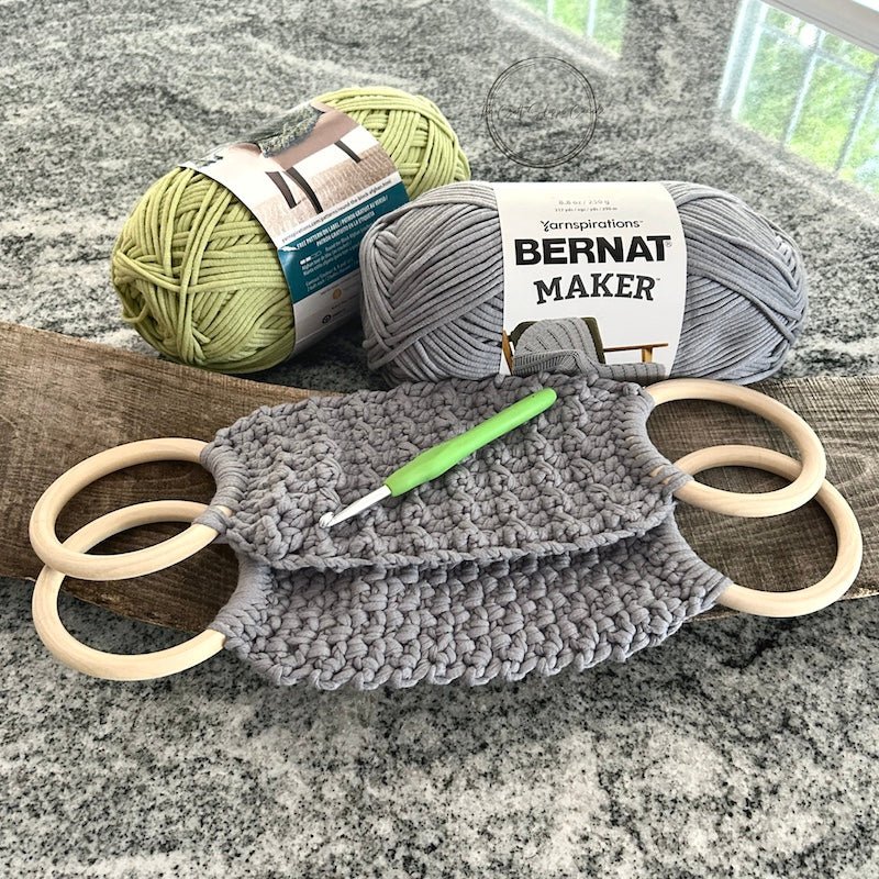 The completed towel holders laying on a wood board with yarn and a crochet hook - The Craft Shoppe Canada