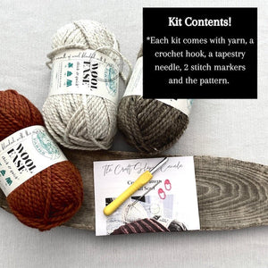 This photo lists the contents of the kit including the pattern, yarn, the optional crochet hook, a tapestry needle, a written pattern and stitch markers - The Craft Shoppe Canada