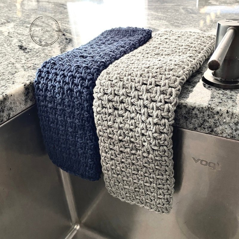 A close up of the navy and grey dishcloths hanging over a sink - The Craft Shoppe Canada