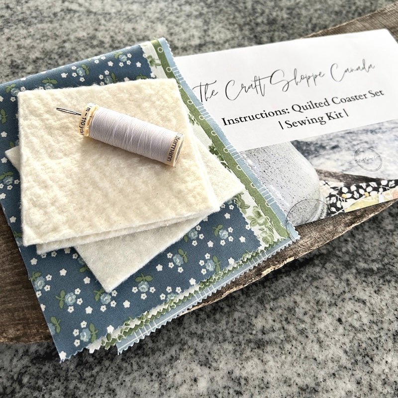 A DIY sewing kit for a quilted coaster set. The finished coaster set is laying on a wooden board - The Craft Shoppe Canada