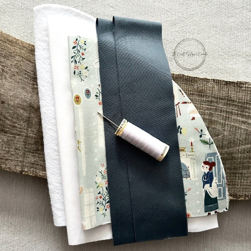 All of the fabric pieces needed for this DIY sewing kit are on top of each other with a spool of white thread on top - The Craft Shoppe Canada